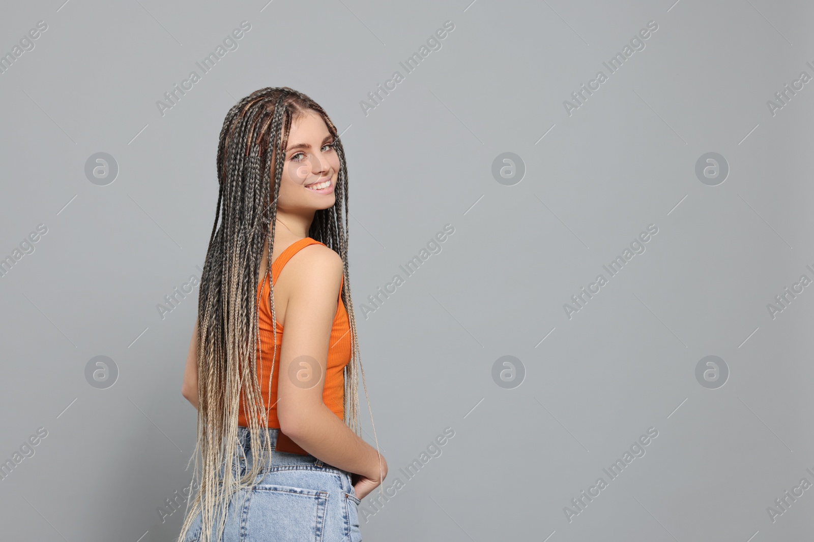 Photo of Beautiful woman with long african braids on grey background, space for text