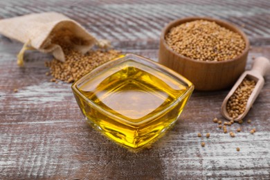 Photo of Bowl with natural oil and mustard seeds on wooden table