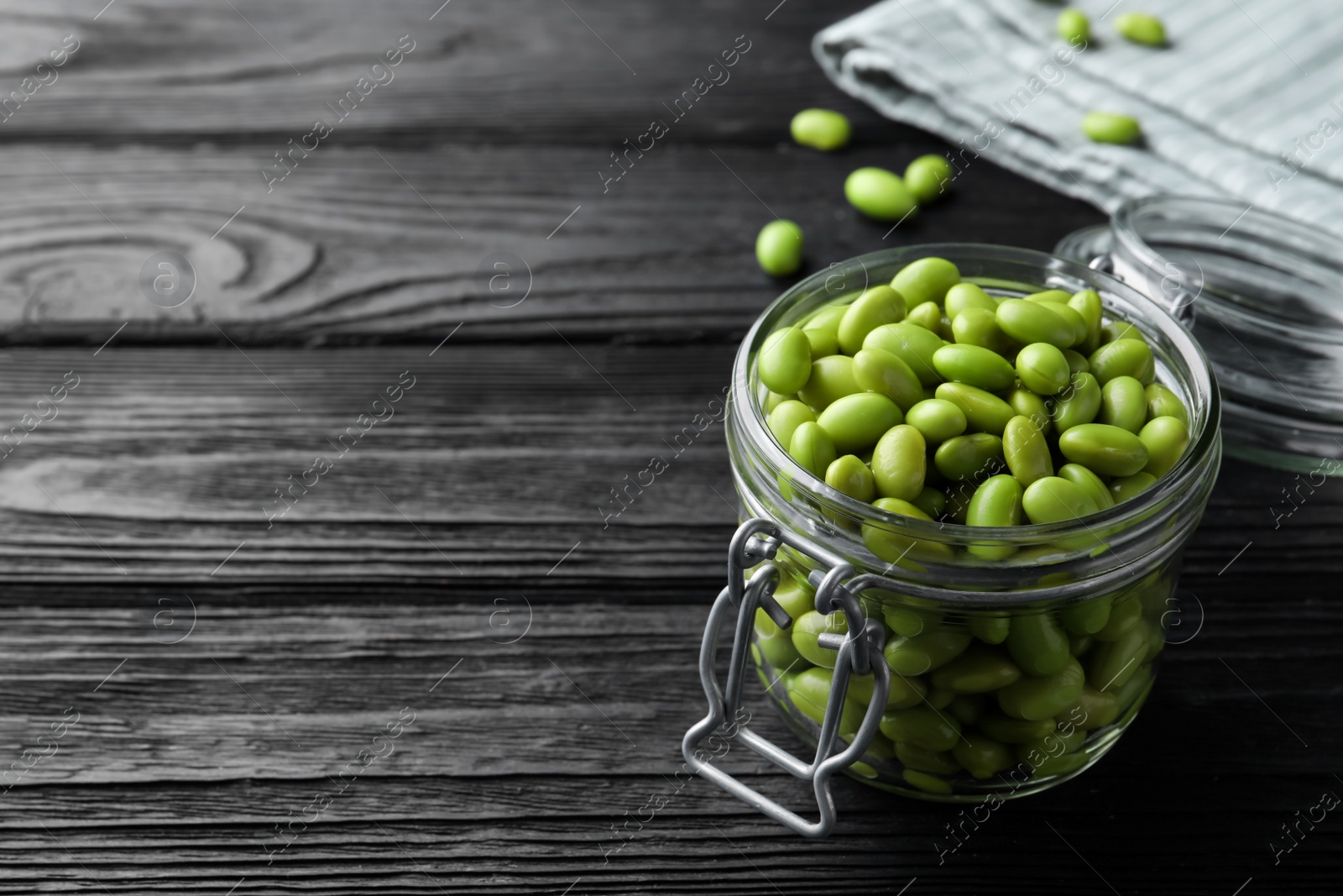 Photo of Jar of edamame beans on black wooden table, space for text