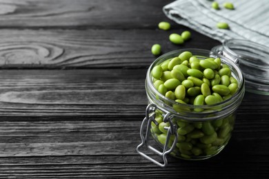 Photo of Jar of edamame beans on black wooden table, space for text