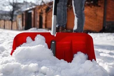 Photo of Person shoveling snow outdoors on winter day, closeup