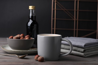 Mug of delicious coffee with hazelnut syrup on wooden table