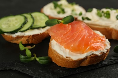 Delicious sandwiches with cream cheese and other ingredients on black table, closeup