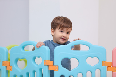 Photo of Cute little child playing in modern playpen at home