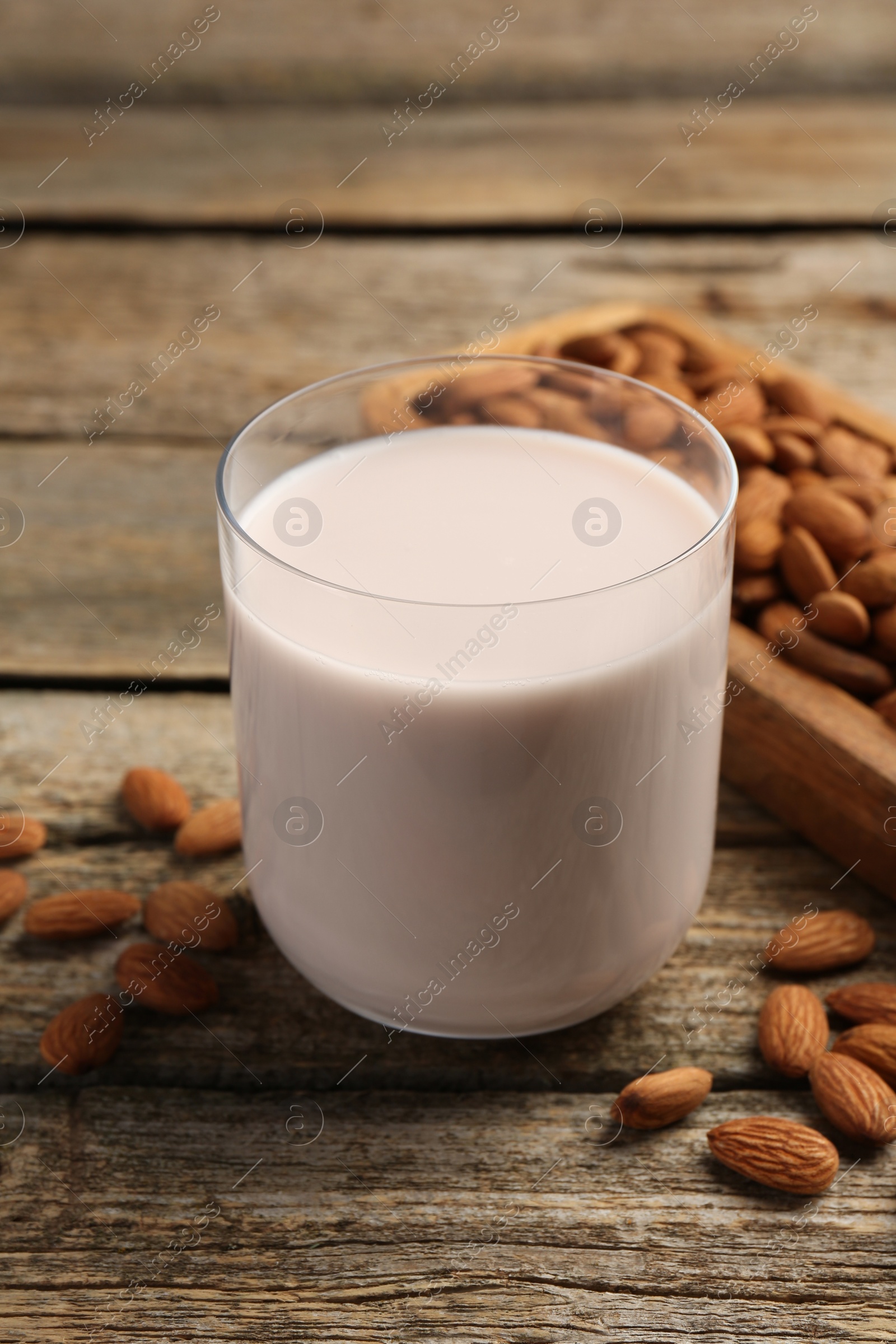 Photo of Glass of almond milk and almonds on wooden table