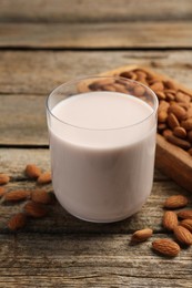 Photo of Glass of almond milk and almonds on wooden table