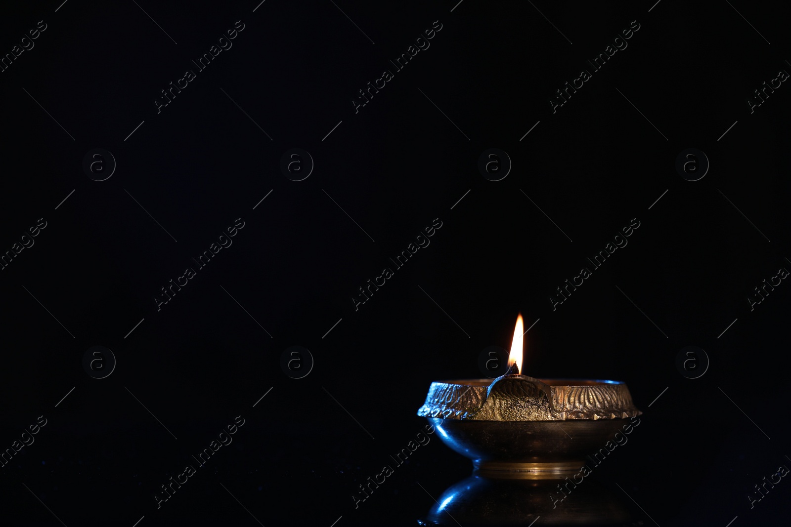 Photo of Lit diya on black background, space for text. Diwali lamp