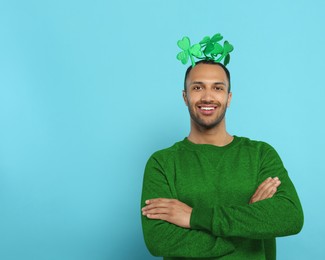 St. Patrick's day party. Man with green clover headband on light blue background. Space for text