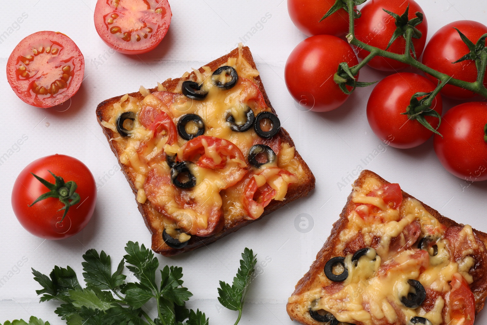 Photo of Tasty pizza toasts, fresh tomatoes and parsley on white tiled table, flat lay