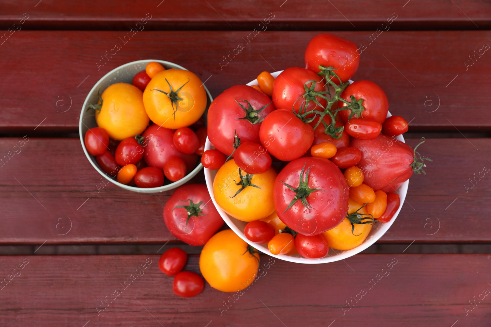 Photo of Bowls with fresh tomatoes on wooden table, flat lay