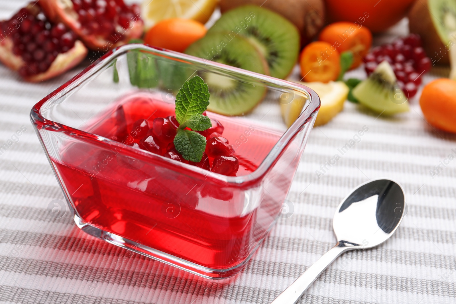 Photo of Glass bowl of tasty jelly and spoon on table