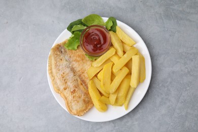 Photo of Delicious fish and chips with ketchup, spinach and lettuce on gray table, top view