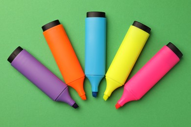 Photo of Bright color markers on green background, flat lay