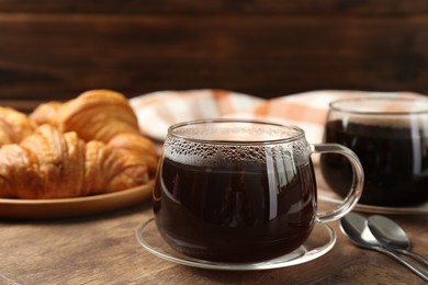 Photo of Hot coffee in glass cup on wooden table, closeup