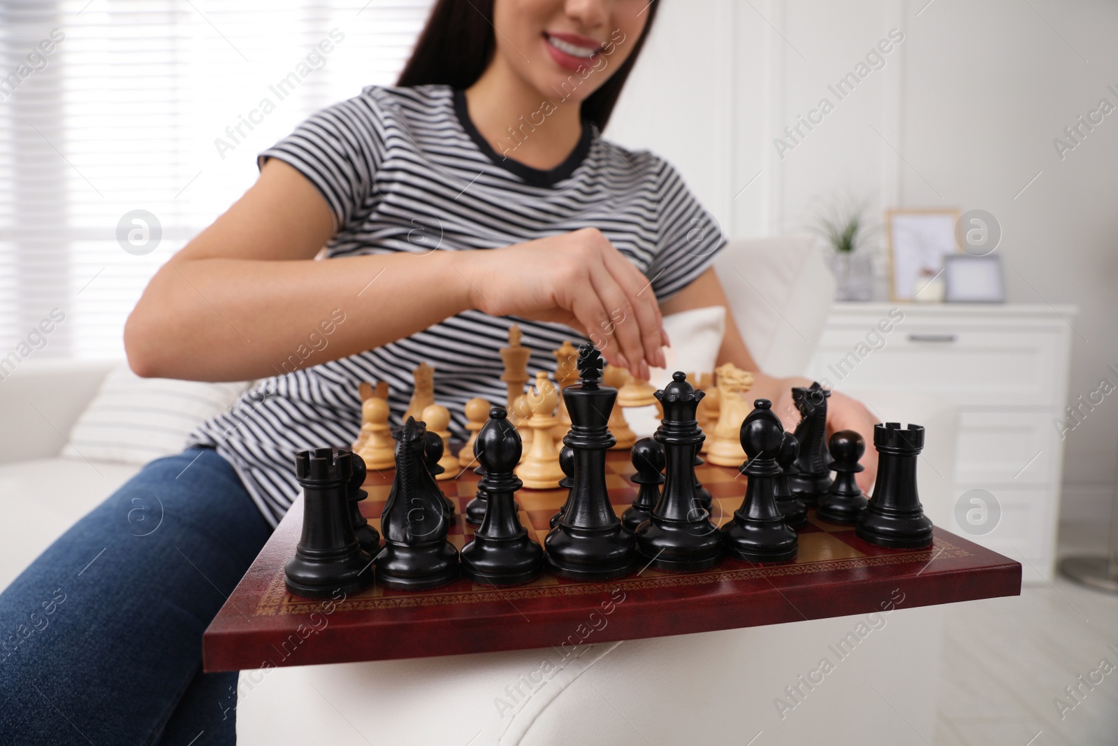 Photo of Woman playing chess on sofa at home, closeup