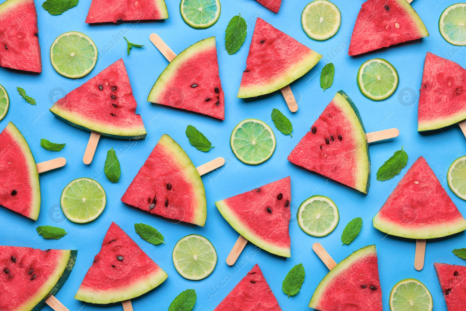 Photo of Tasty sliced watermelon and limes on light blue background, flat lay