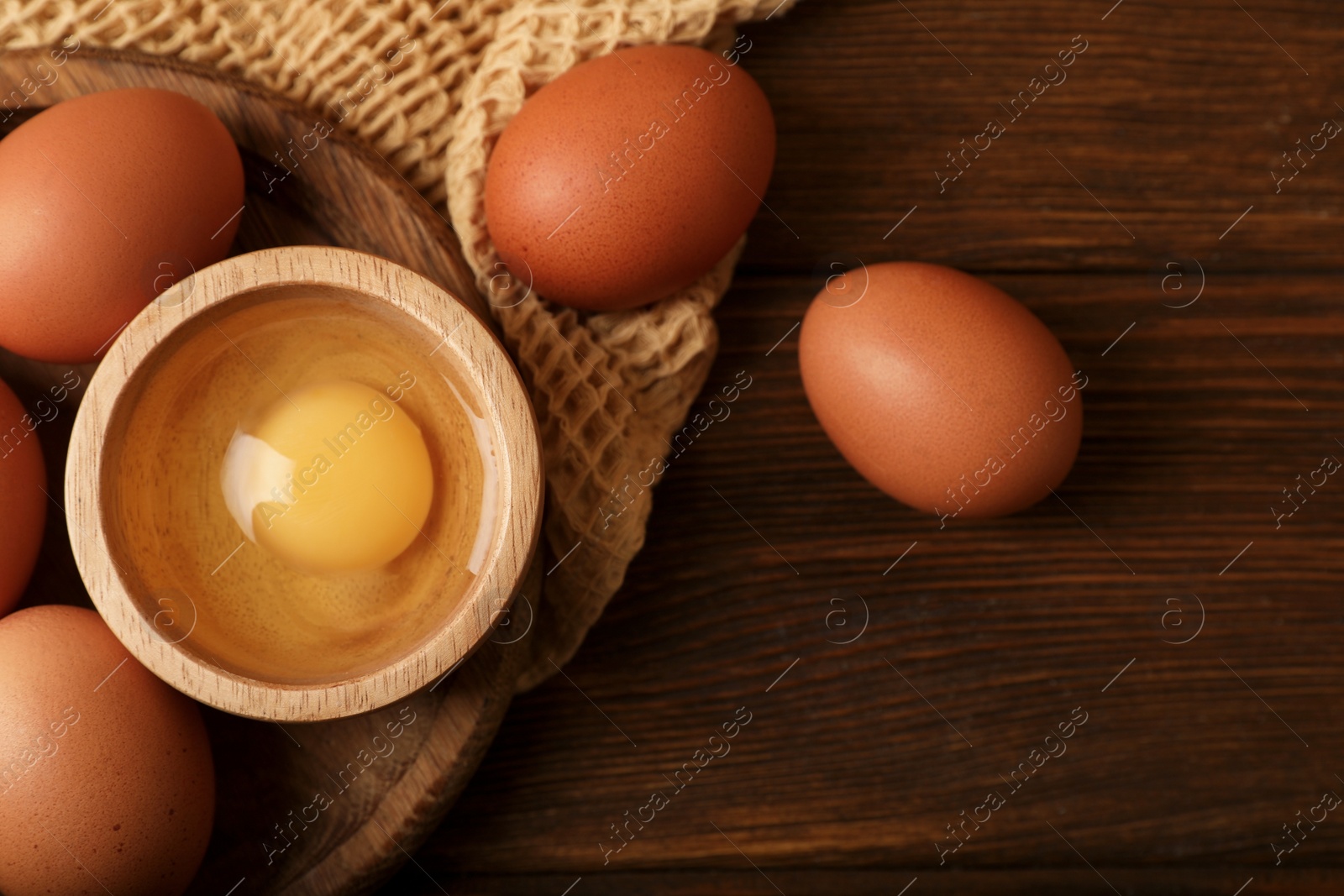 Photo of Raw chicken eggs on wooden table, flat lay. Space for text