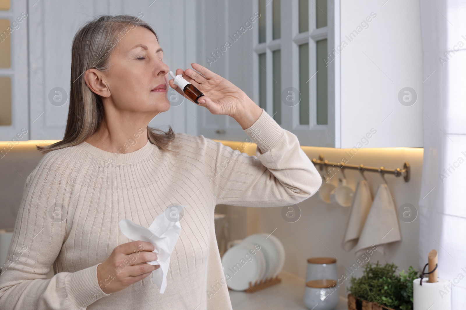 Photo of Medical drops. Woman using nasal spray indoors