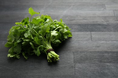 Photo of Bunch of fresh coriander on black wooden table. Space for text