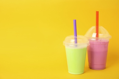 Photo of Plastic cups of tasty milk shakes and space for text on color background