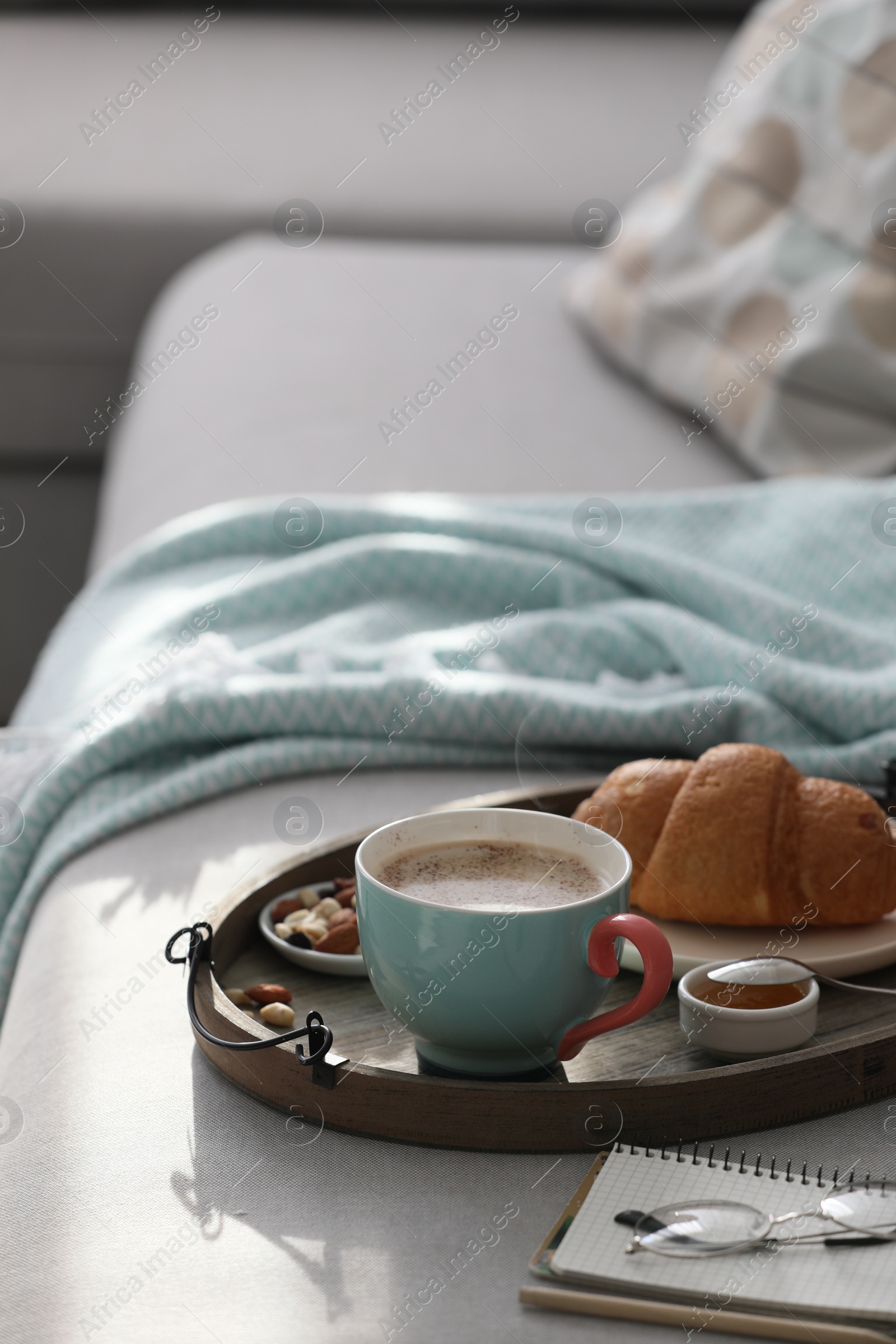 Photo of Tray with tasty breakfast on grey sofa in morning.  Space for text