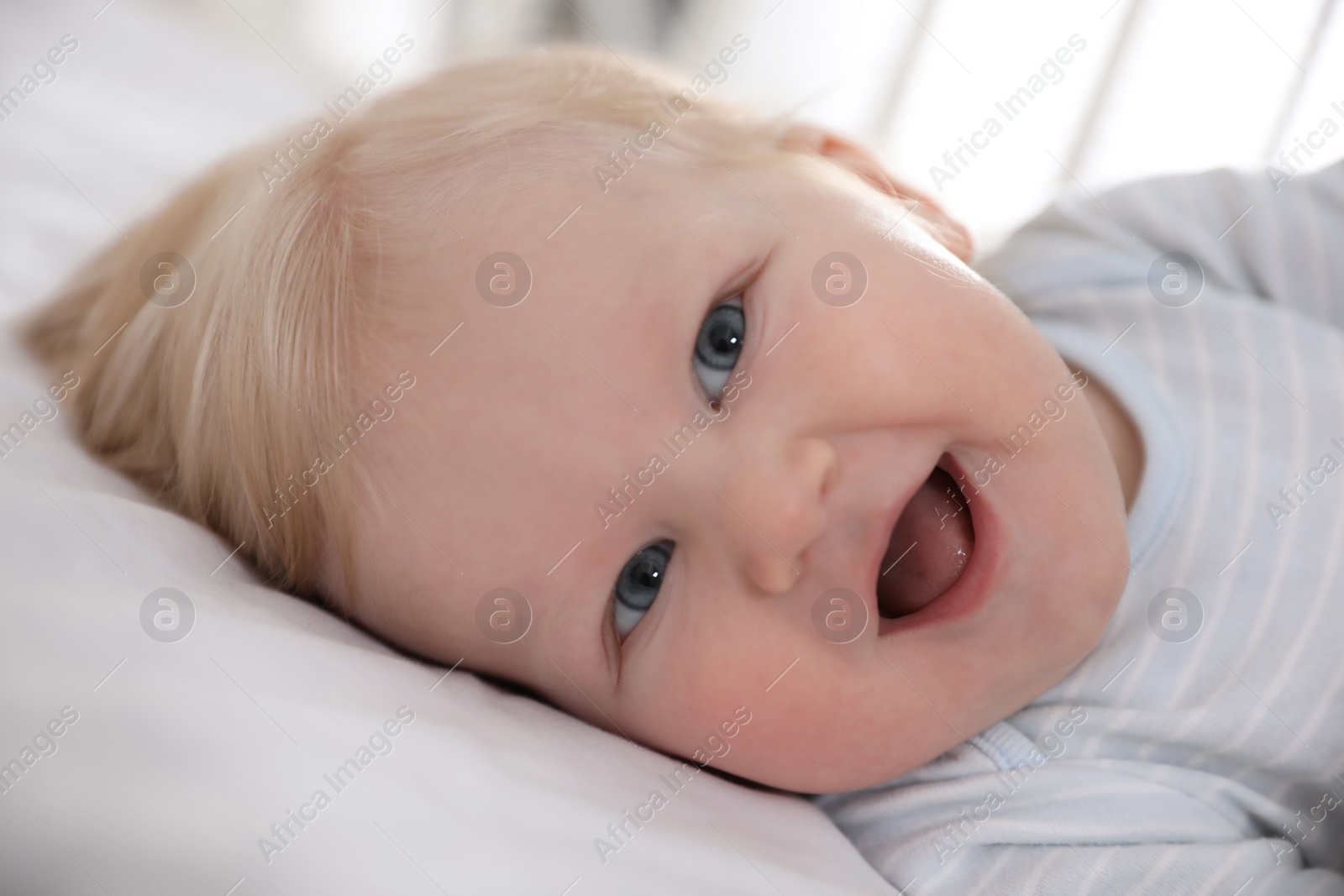 Photo of Cute little baby lying in crib, closeup. Bedtime