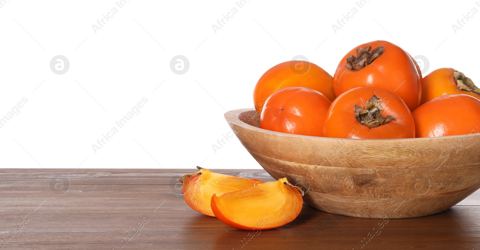 Photo of Delicious ripe juicy persimmons with bowl on wooden table against white background