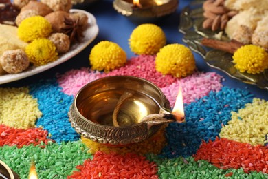 Photo of Diwali celebration. Diya lamps and colorful rangoli on table, closeup