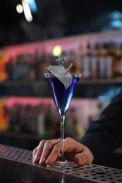 Bartender with fresh alcoholic cocktail at bar counter, closeup
