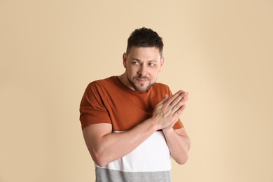 Photo of Greedy man rubbing hands on beige background