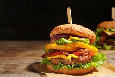 Photo of Tasty burger with bacon on table. Space for text