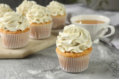 Photo of Tasty cupcakes with vanilla cream on grey table, closeup