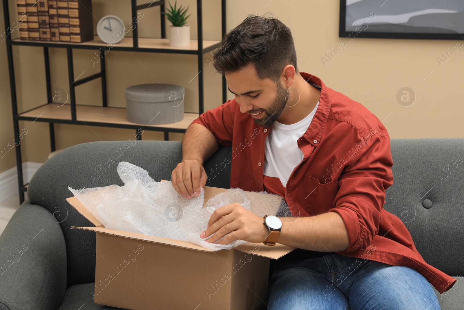 Photo of Man unpacking parcel at home. Online shopping