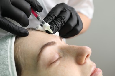 Photo of Cosmetologist giving facial injection to patient in clinic, closeup. Cosmetic surgery