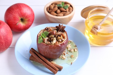 Tasty baked apple with nuts, honey, spices and mint on white wooden table, closeup