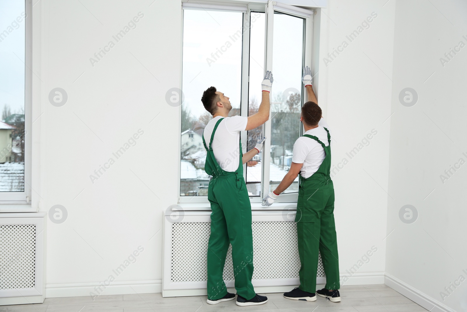 Photo of Construction workers installing plastic window in house