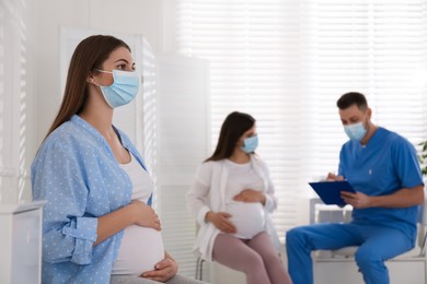 Pregnant woman waiting for appointment while doctor consulting other patient in clinic