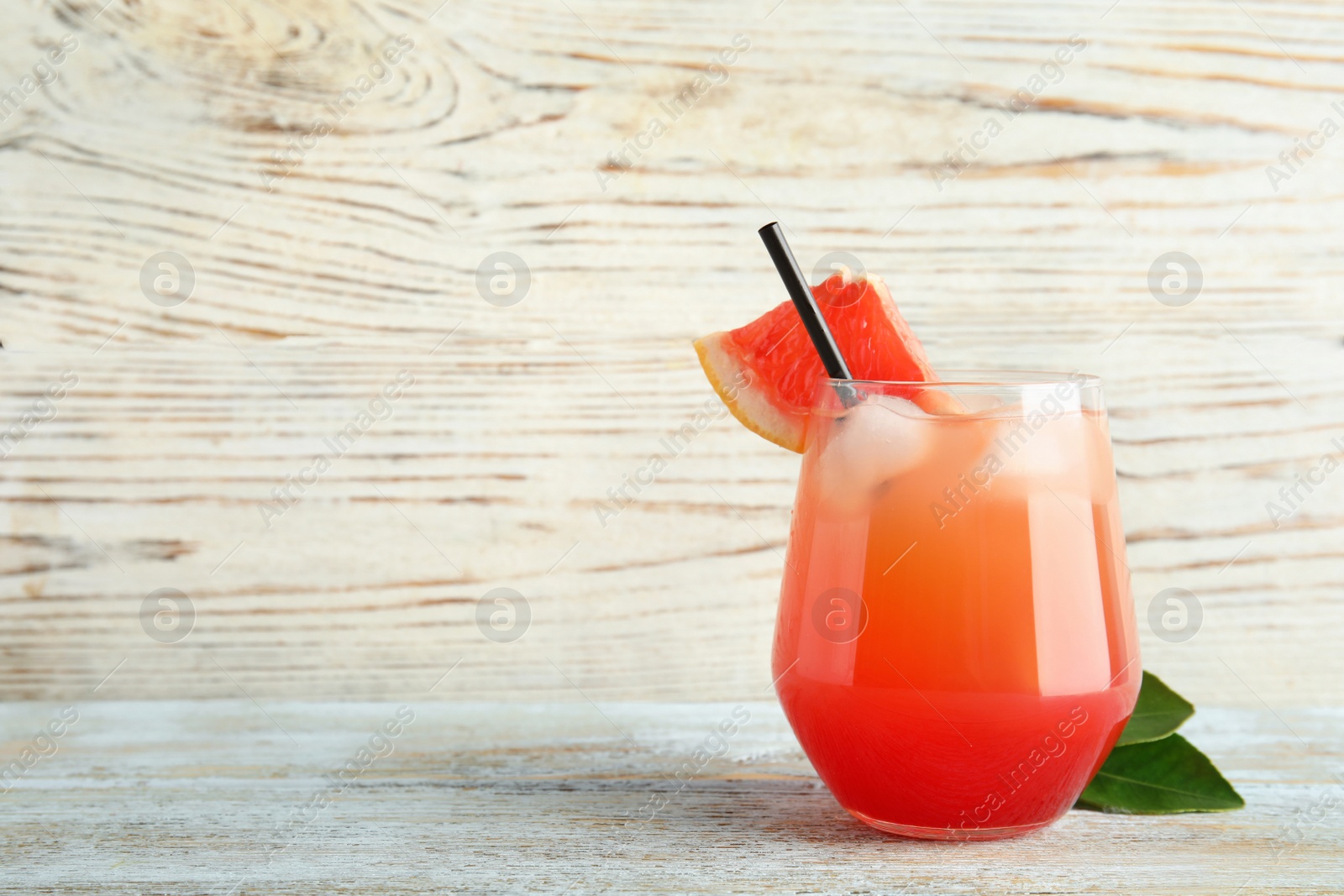 Photo of Glass of grapefruit cocktail on wooden table. Space for text