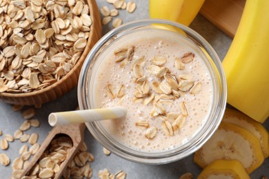 Photo of Glass of tasty banana smoothie with oatmeal on light grey table, flat lay