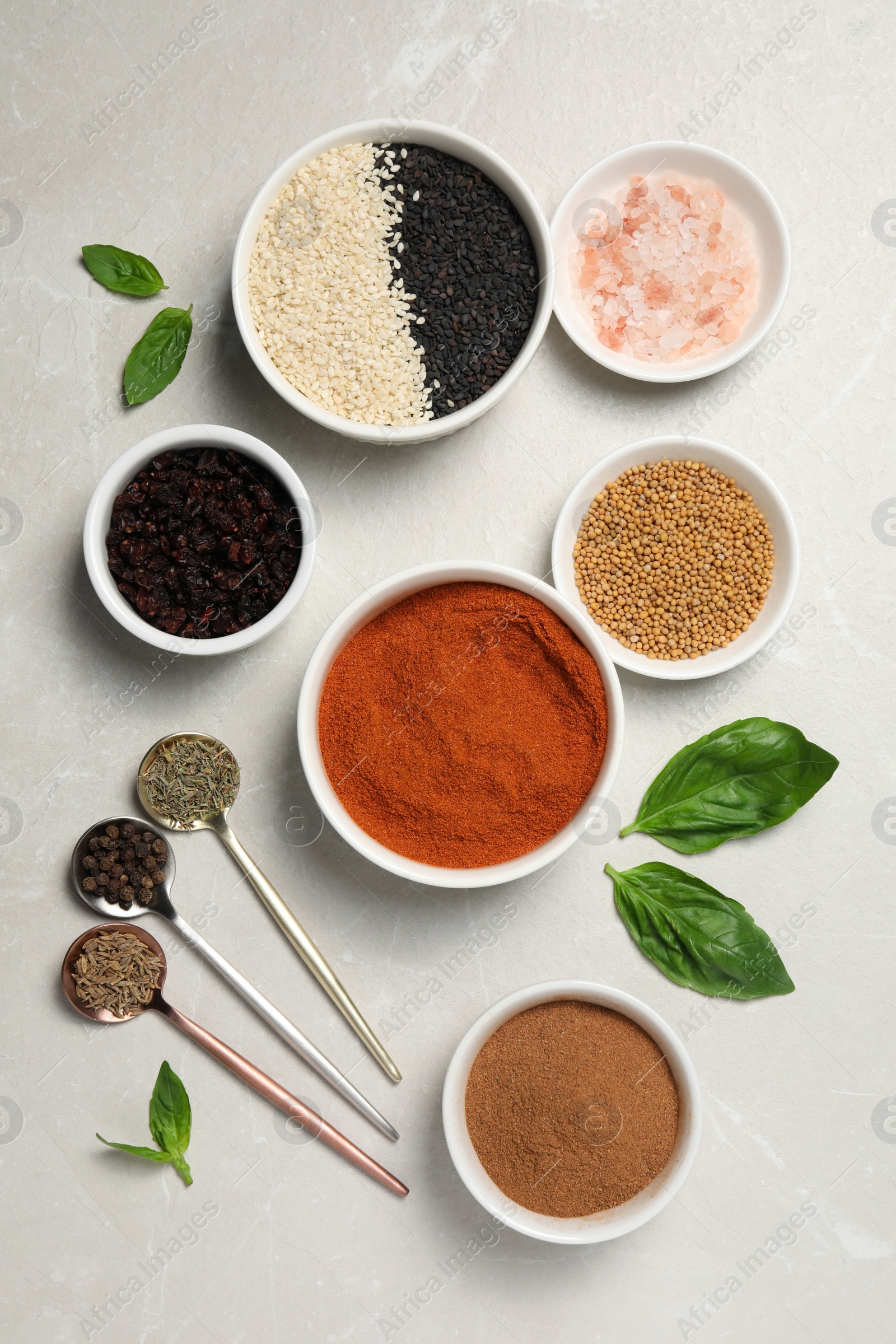 Photo of Bowls and spoons with different spices on light grey marble table, flat lay