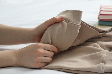 Woman folding clothes on bed, closeup view