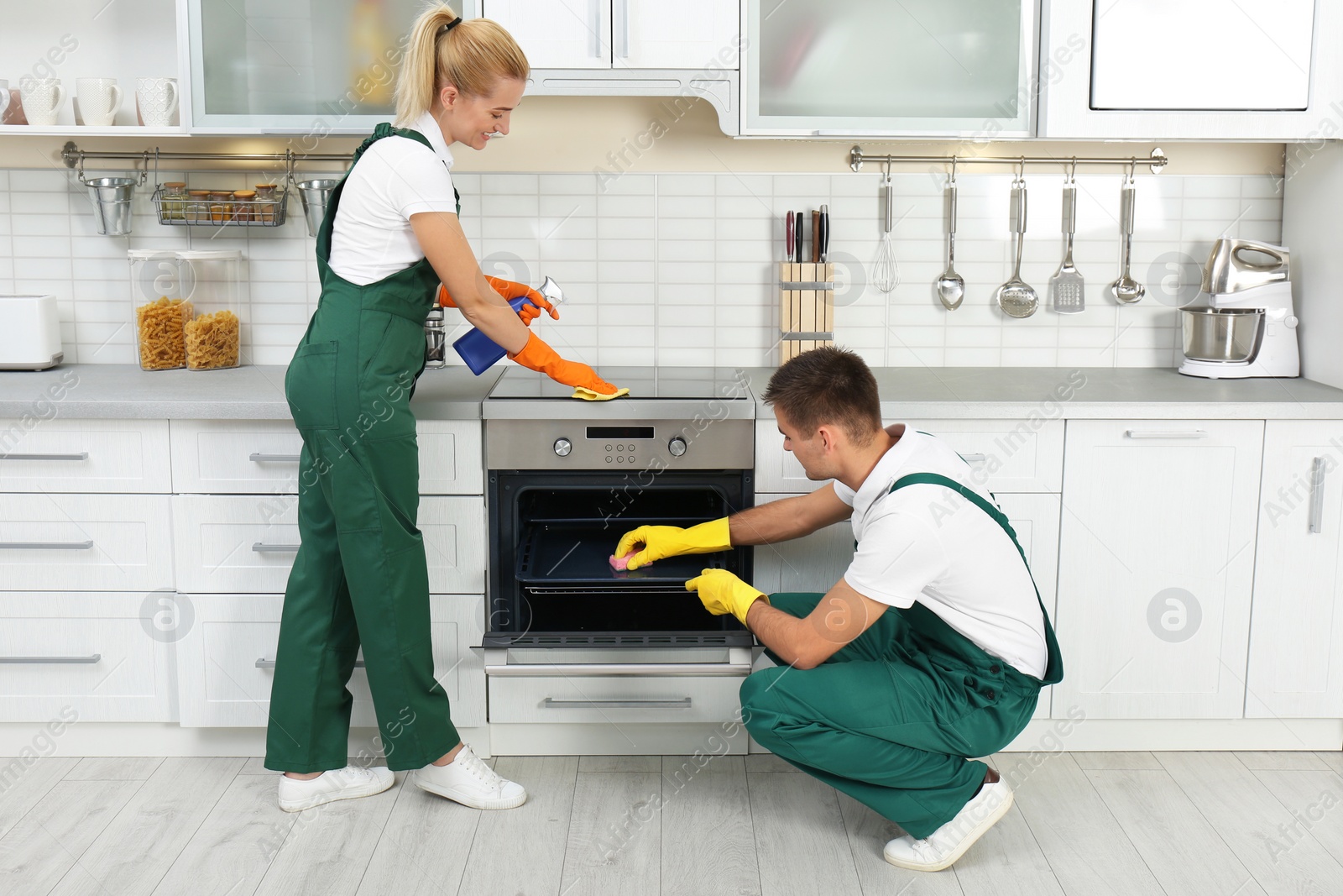 Photo of Team of janitors cleaning kitchen oven in house