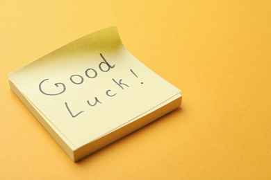 Photo of Note with phrase GOOD LUCK on orange background