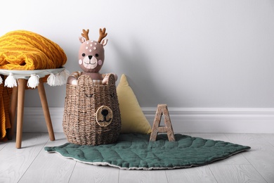 Photo of Wicker basket with cute toy deer in baby room, space for text. Interior design