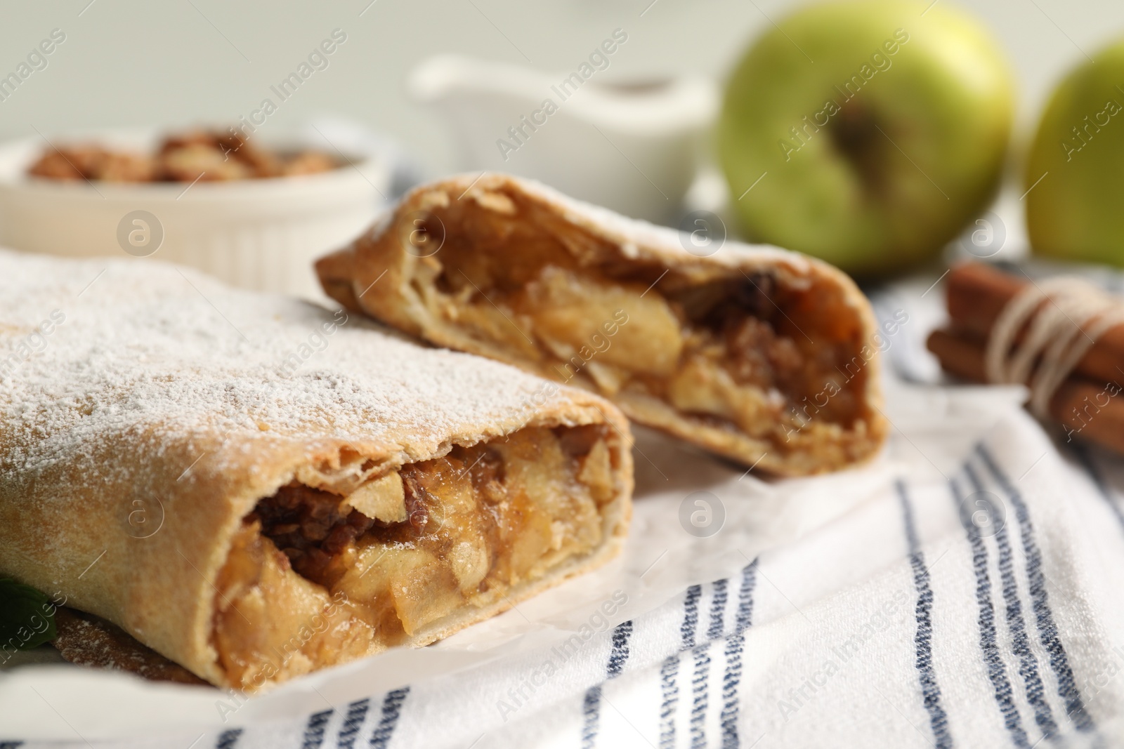Photo of Delicious strudel with apples, nuts and powdered sugar on table, closeup. Space for text