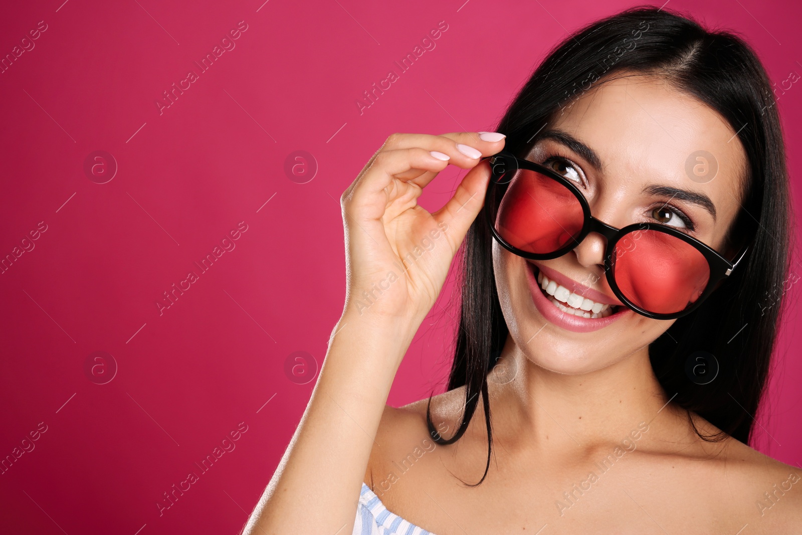 Photo of Beautiful woman wearing sunglasses on pink background, closeup. Space for text