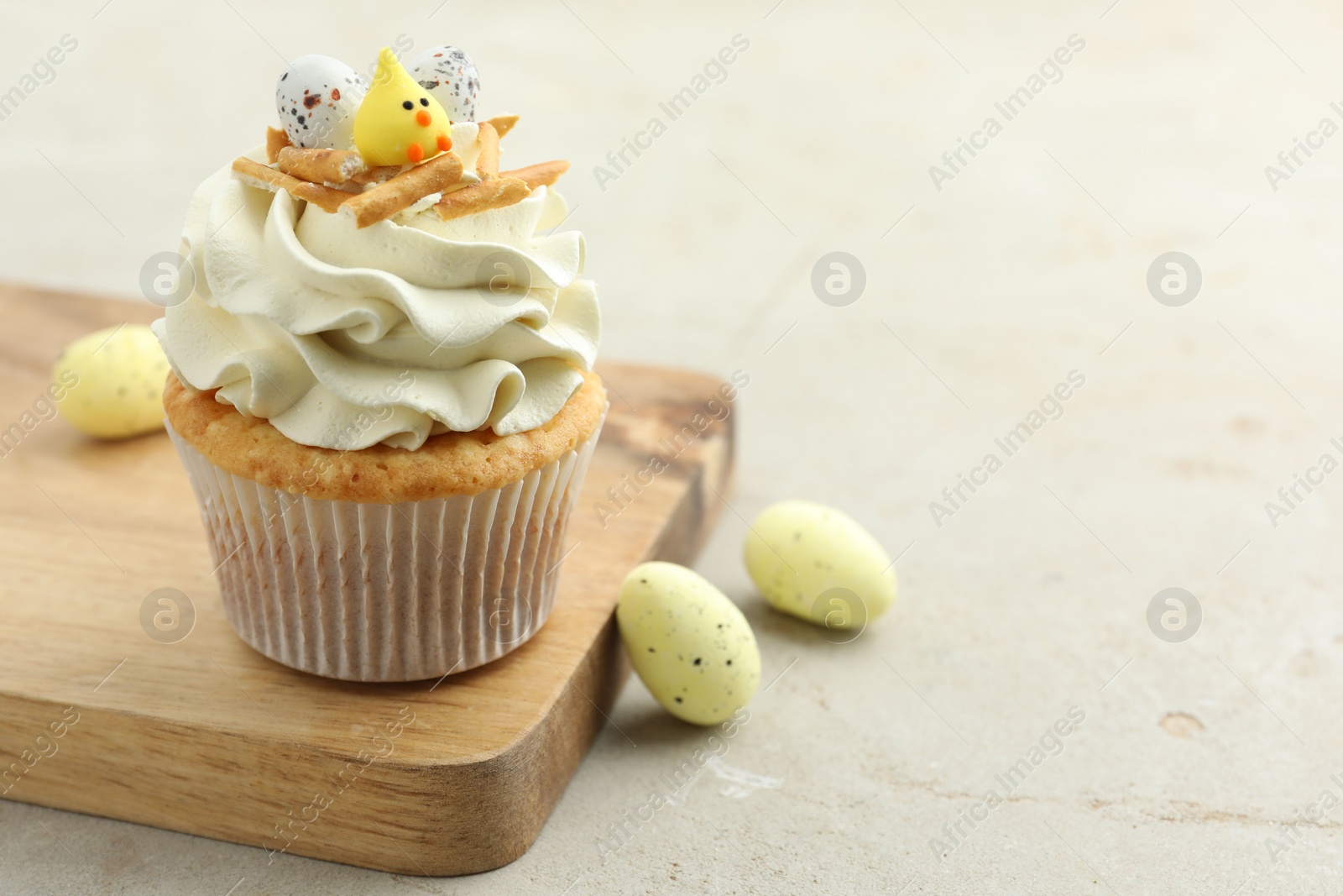 Photo of Tasty Easter cupcake with vanilla cream and candies on gray table, space for text