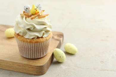 Tasty Easter cupcake with vanilla cream and candies on gray table, space for text