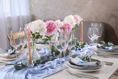 Photo of Beautiful table setting. Plates near glasses, peonies and cutlery on table in room