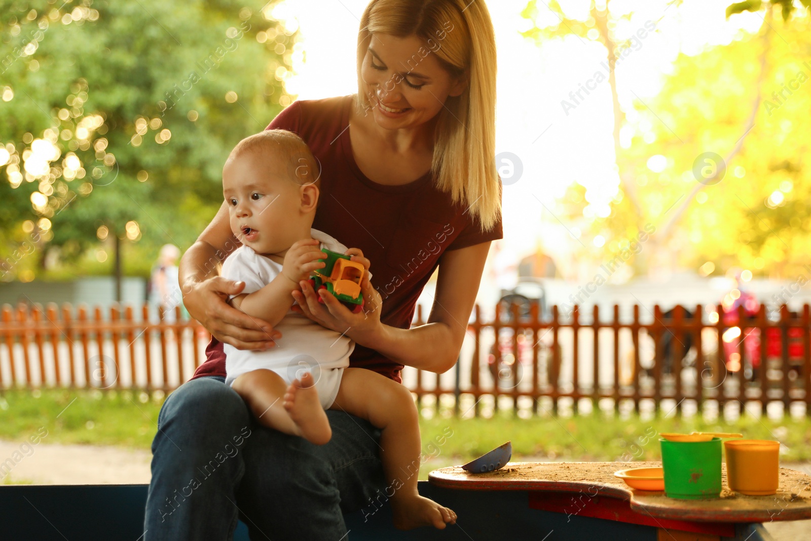 Photo of Nanny and cute little baby playing with toys outdoors